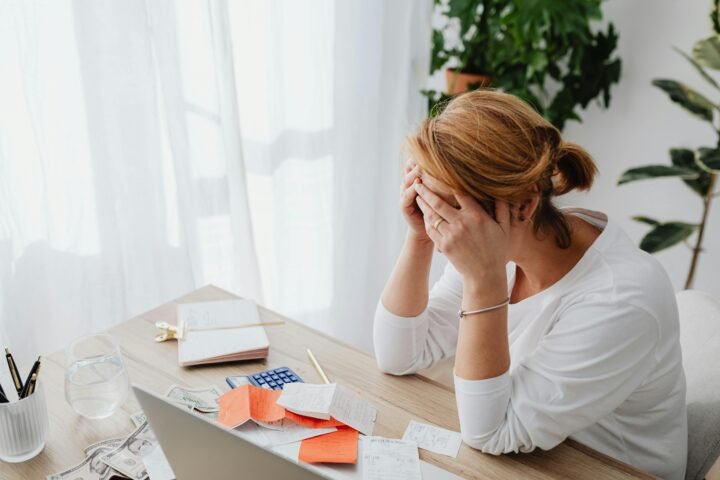 Reviewing finances with a calculator and budget planner to stretch pay cheque and find budgeting hacks.