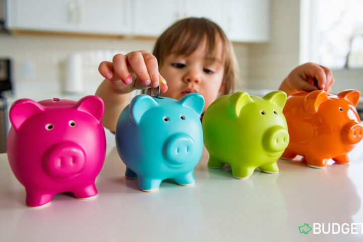 Child placing coins into a colourful piggy bank at home kids saving money