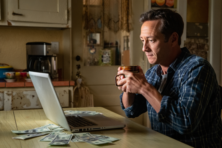 Why saving money feels hard even when you earn enough, person reflecting over household finances at the kitchen table