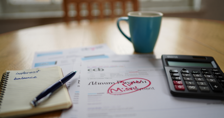 Credit card statement highlighting a minimum payment while reviewing household finances at home.