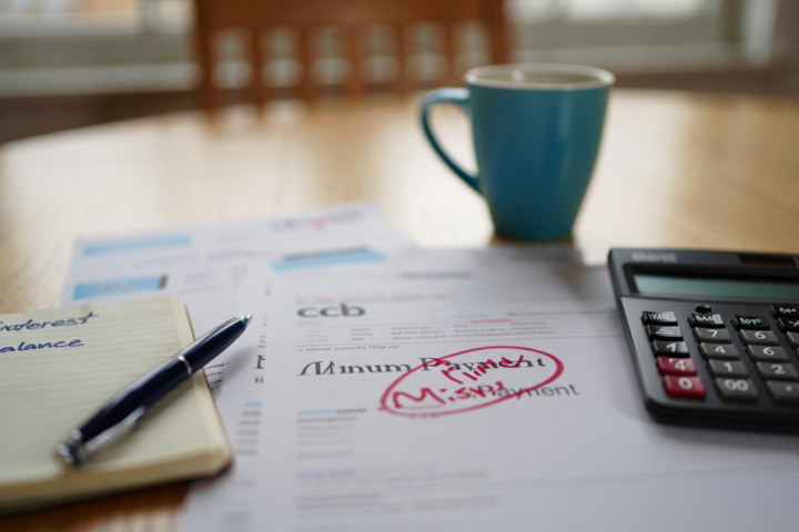 Credit card statement highlighting a minimum payment while reviewing household finances at home.